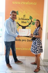 Symbolický šek ve výši 25 000 korun převzala z rukou Milana Bláhy, zástupce ČEZ Teplárenské,  ředitelka ZŠ  Za Chlumem v Bílině  Barbora Schneiderová. Jak dokazuje fotoaparát,  škola si již za celou částku pořídila pomůcky pro výuku Digitální technologie a Informatiky.